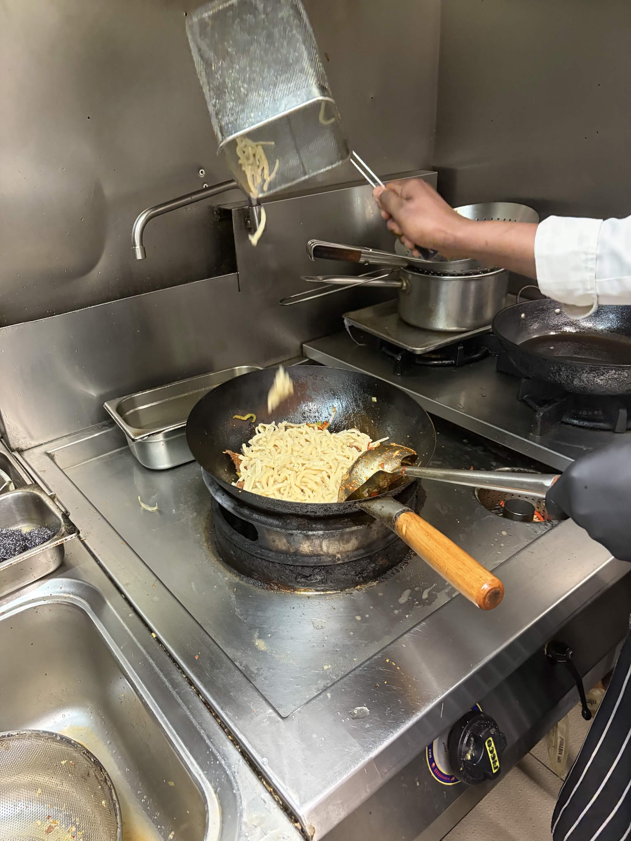 Les nouilles plongent dans le wok avant le sautage
