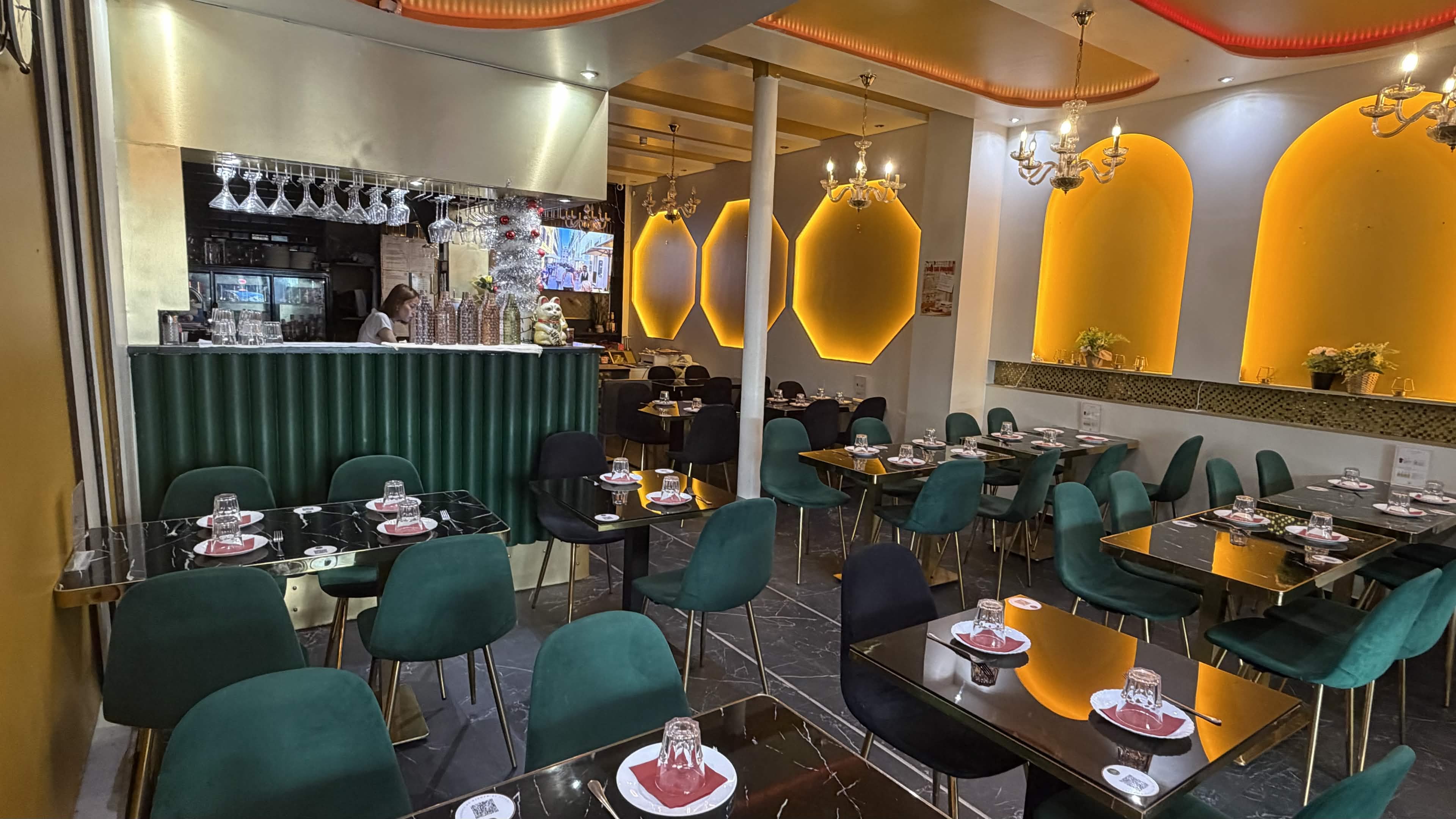Salle du restaurant Le 831 : fauteuils en velours émeraude, lanternes dorées et comptoir vert profond